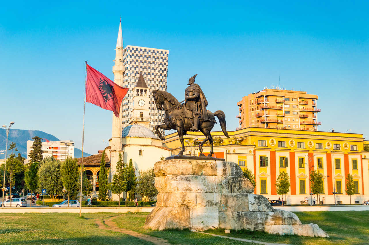Vue sur une célèbre statue de Tirana, le grand drapeau albanais ainsi que la mosquée Et'Hem Bey