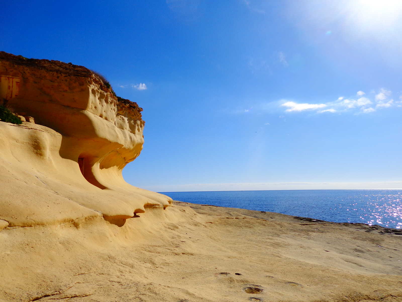 Falaise de calcaire érodé en une vague par le vent, le ciel bleu et la mer sont toujours présents © Tony Viguier