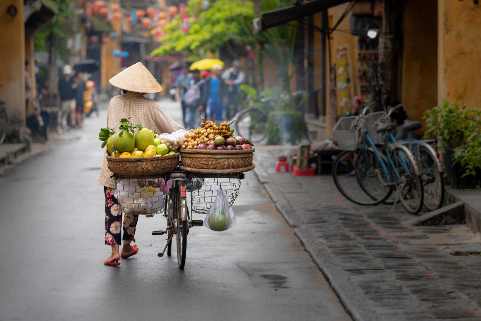Femme marchant à Hoi An avec des fruits au Vietnam © Viktor