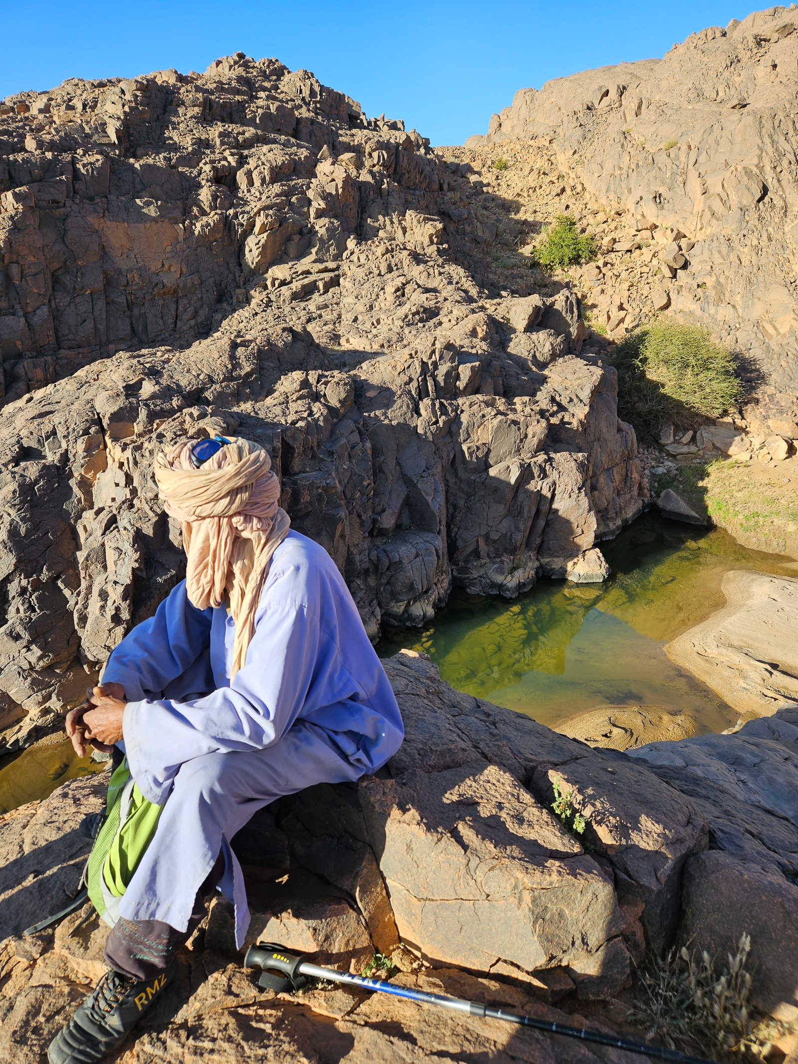 Guide Touareg devant une vasque d'eau dans l'oued Tamanrasset, en Algérie © Andrevon Pénélope