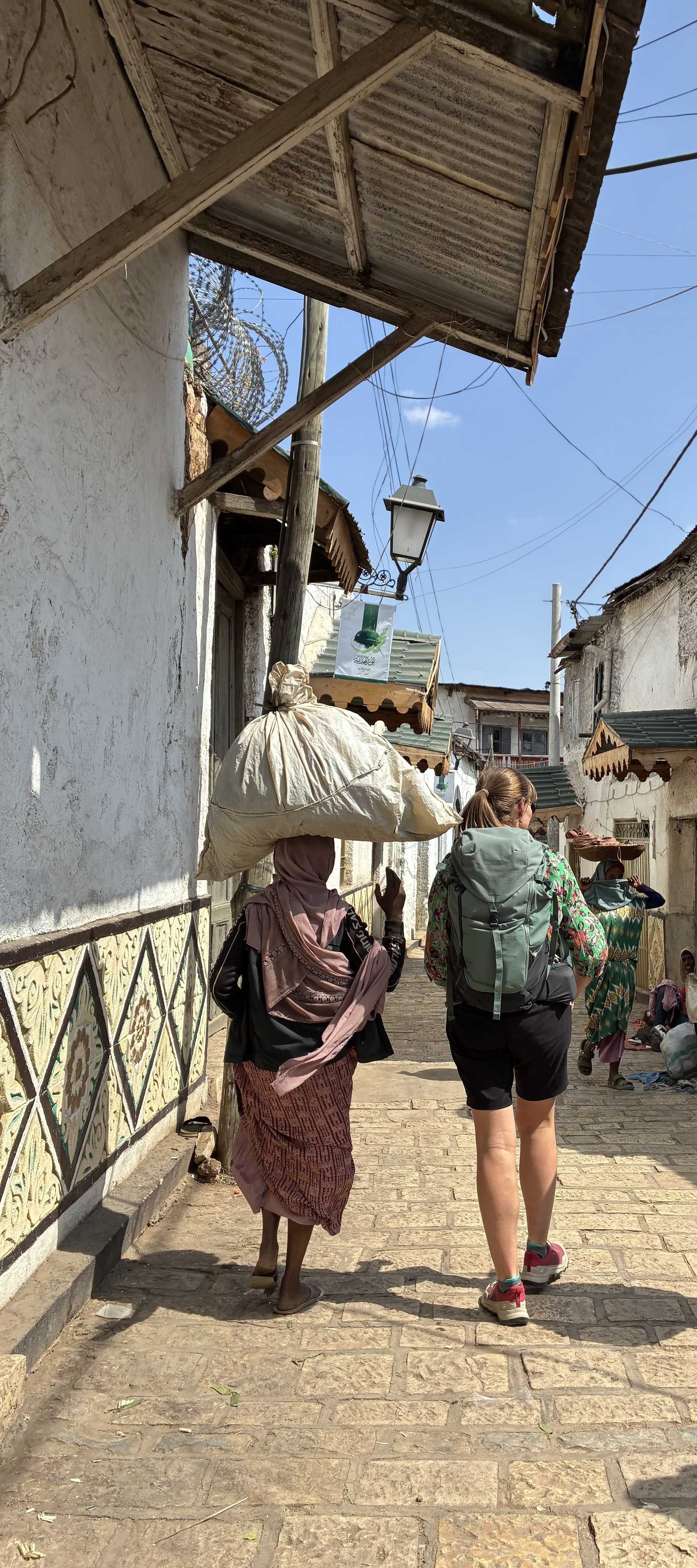 Voyageuse marchant avec une femme locale dans la cité d'Harar © Geny Alice