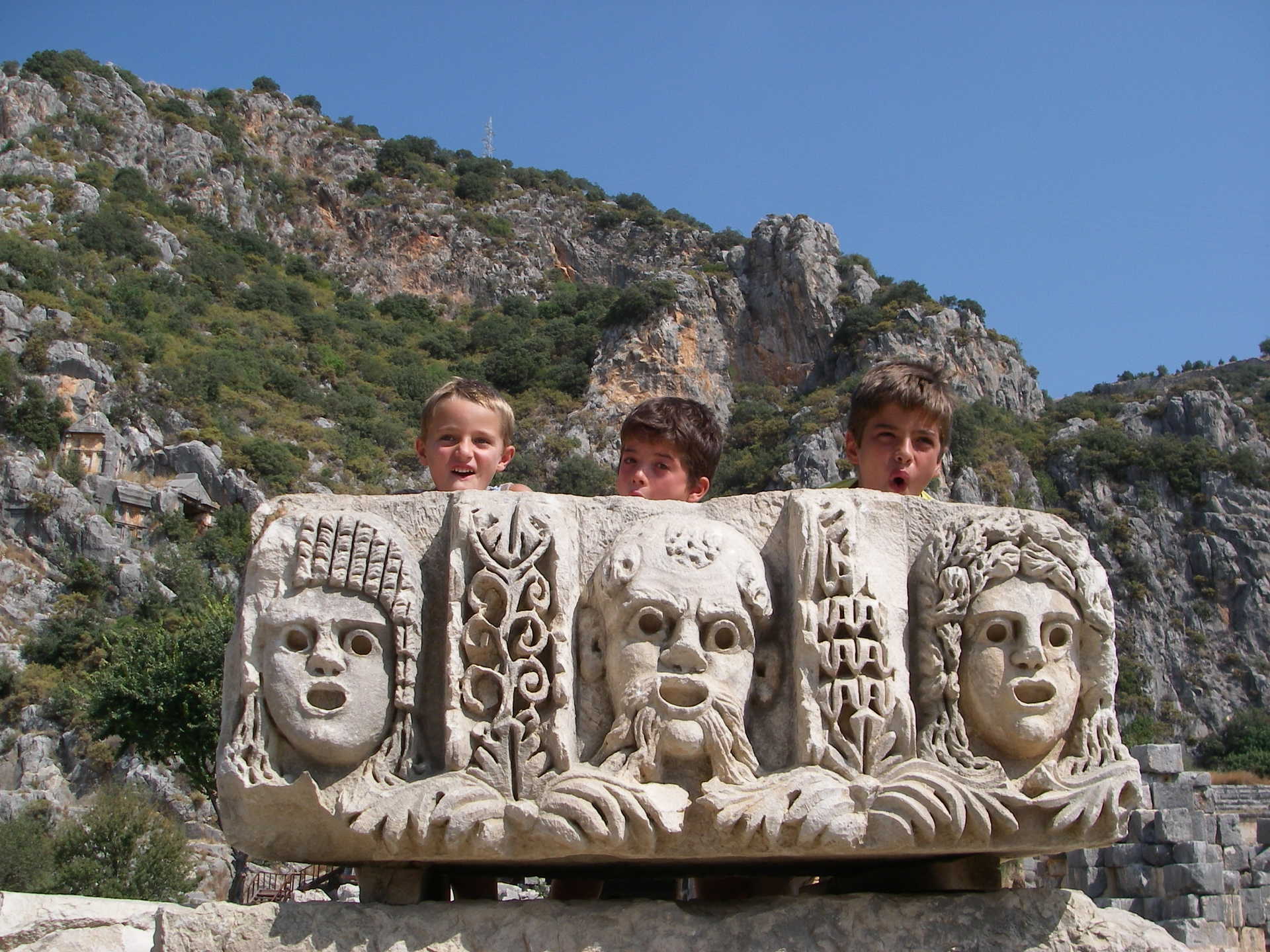 Enfants se cachant derrière un morceau de pierre sculptée