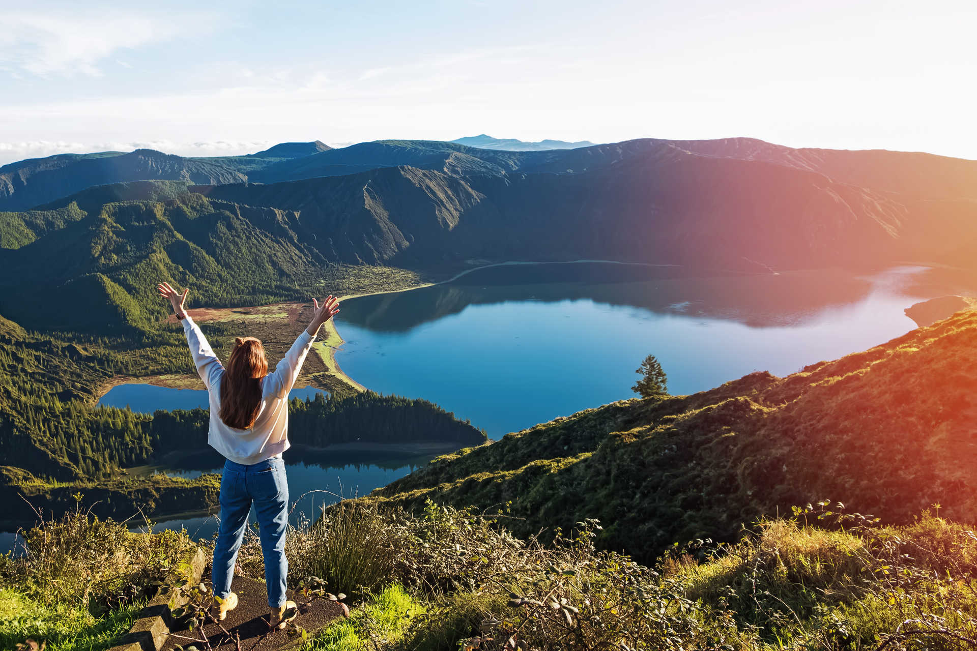 Femme levant les bras en face du lac de la montagne São Miguel, Azores
