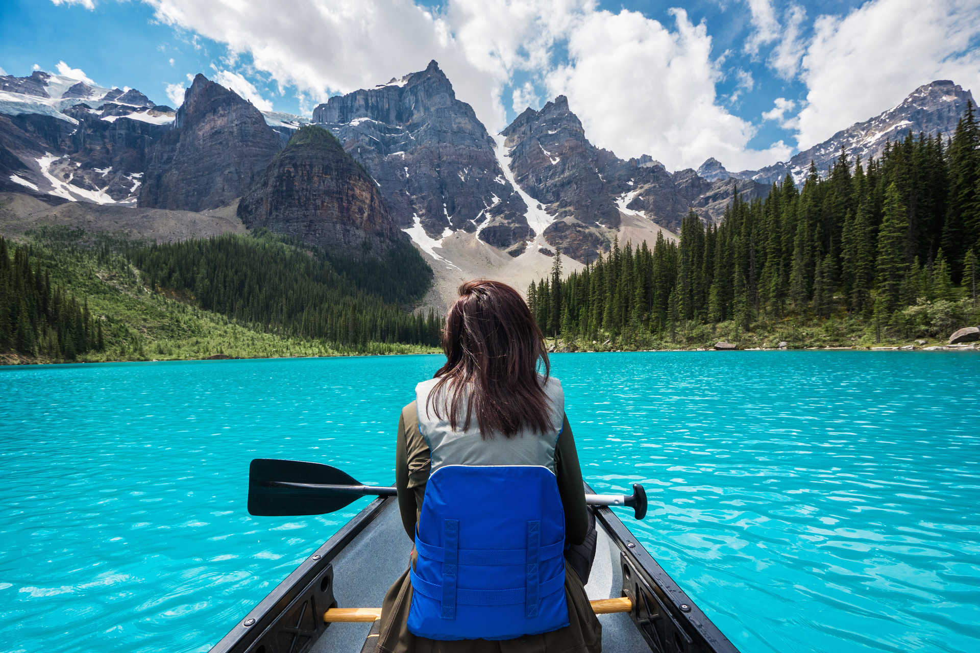 Jeune femme en canoe kayak sur le lac de Banff en Alberta au Canada face aux montagnes du parc national