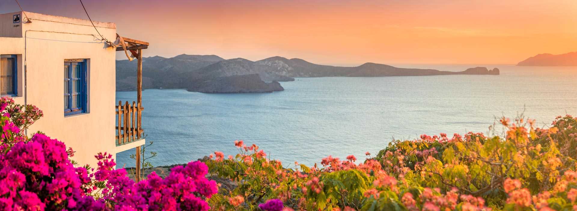 Maison et bougainvillier devant un coucher de soleil sur la baie des Cyclades, en Grèce