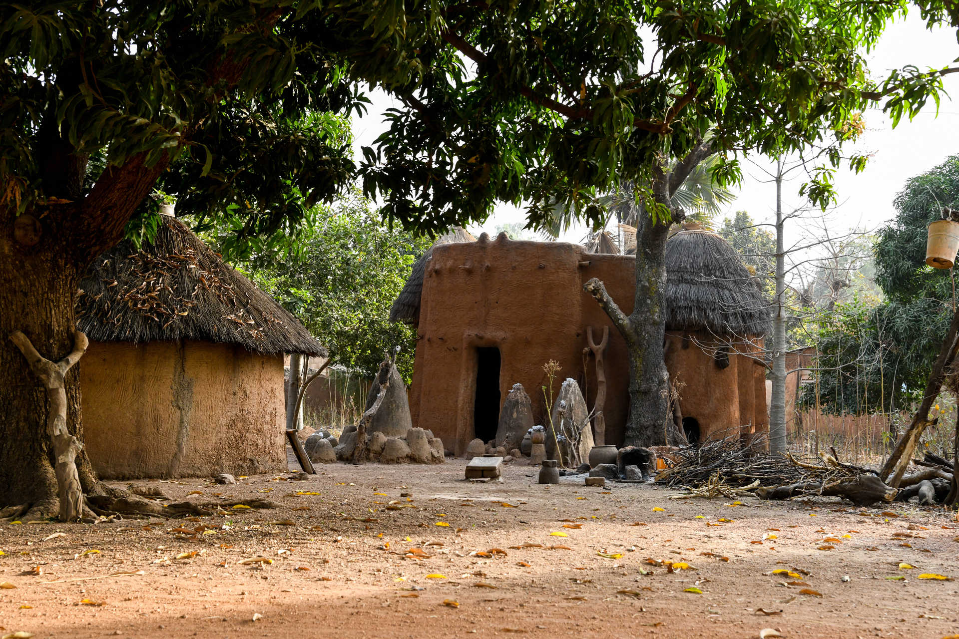 Maison traditionnelle béninoise tata somba avec du bois de chauffage et un hamac suspendu à un arbre