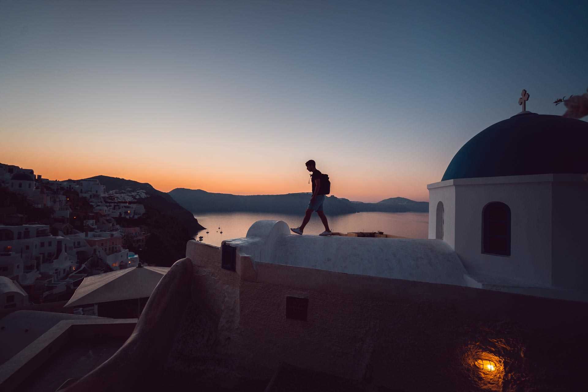 Randonneur sur des toits de Santorin au coucher du Soleil