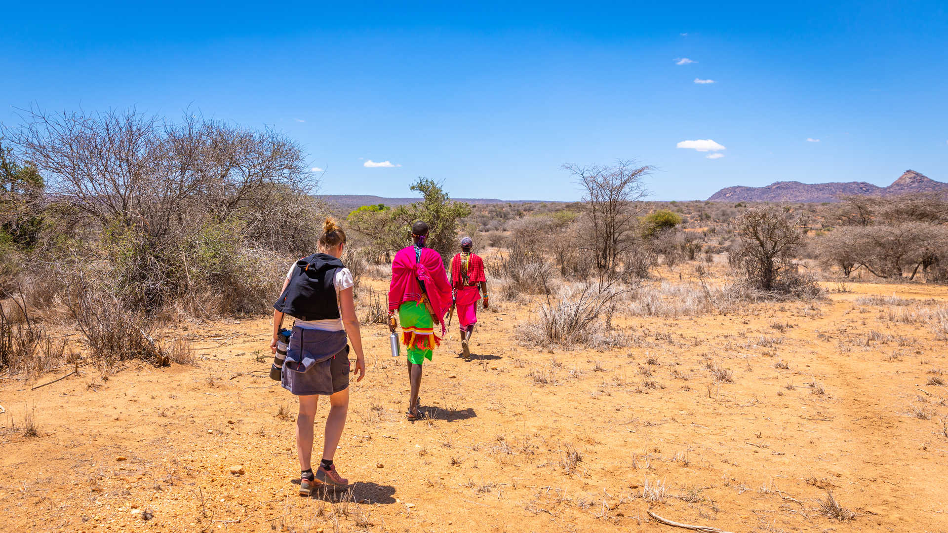 Randonneuse et masai marchant dans la savane au Kenya