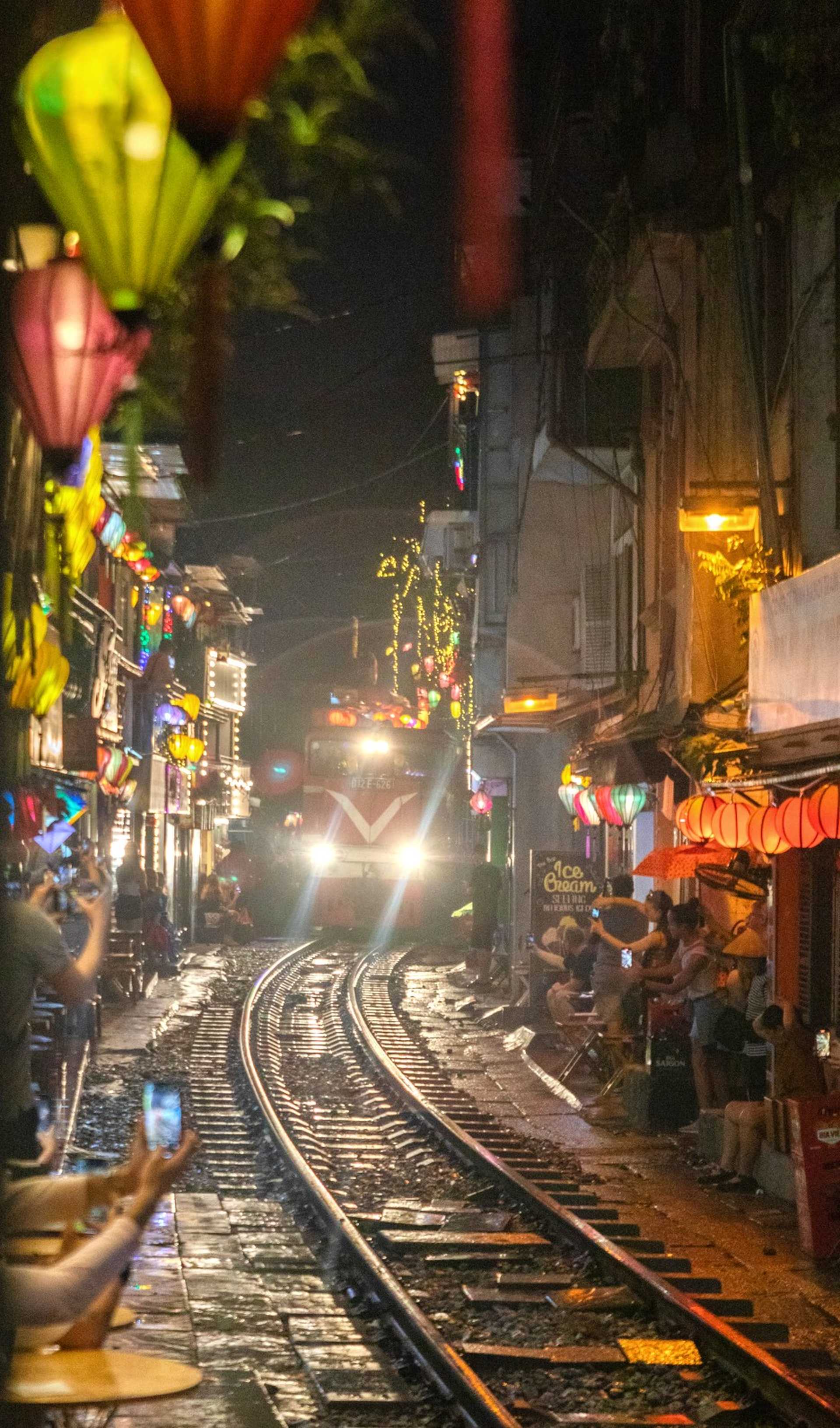 rue traversée par un train de nuit à Hanoï au Vietnam