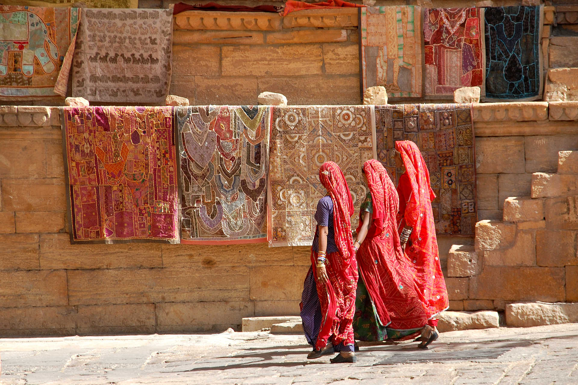 Trois indiennes en sari marchants devant un mur coloré, Rajasthan