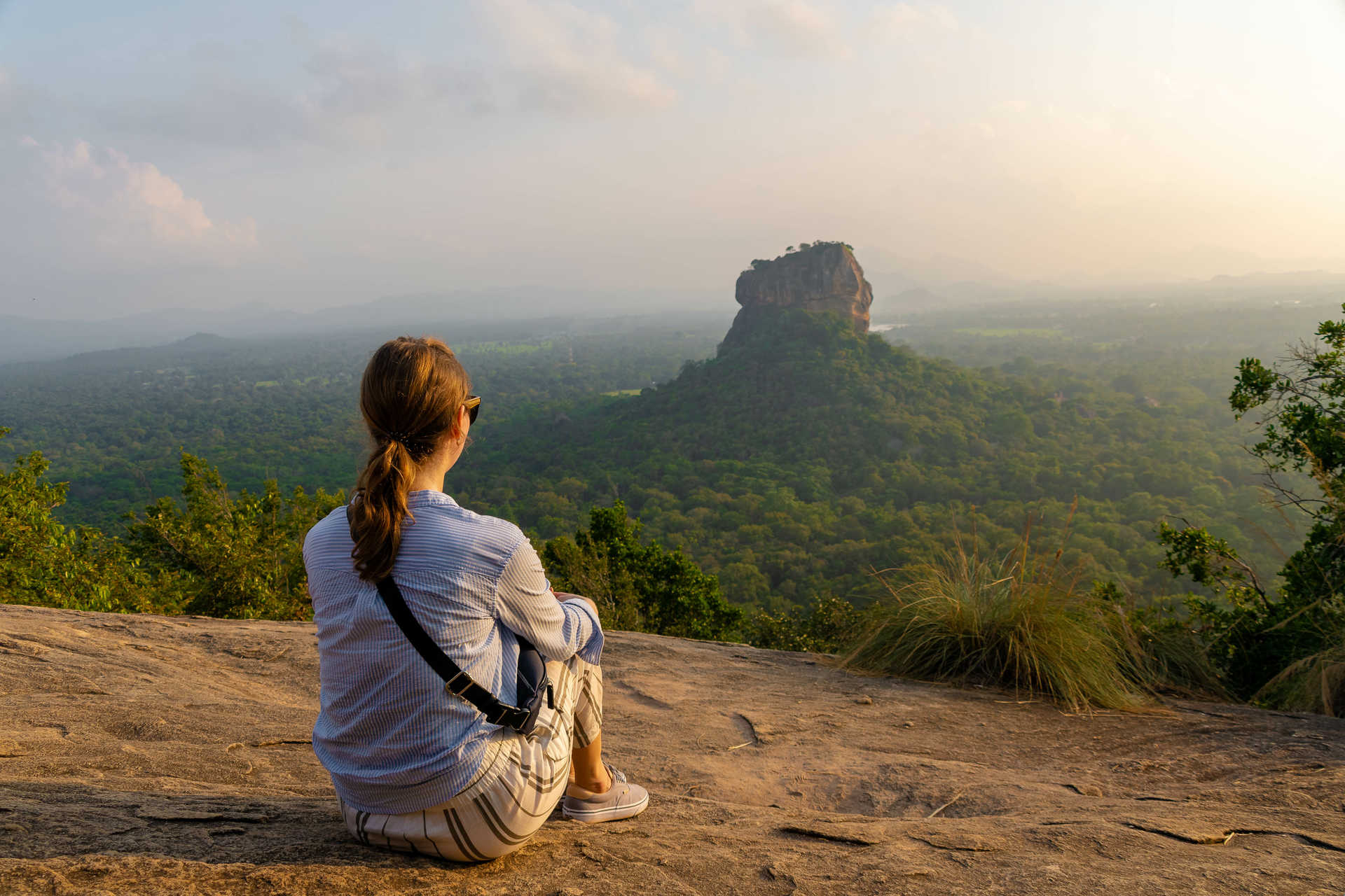 Voyageuse de dos observant le coucher de soleil depuis le rocher de Pidurangala au Sri Lanka