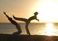 Deux jeunes-hommes faisant de la capoeira sur la plage au Brésil