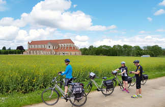 Des cyclistes devant une champ fleuri et l'abbaye de Pontigny en arrière-plan