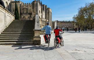 Deux personnes sur les vélos devant la place centrale d'Avignon en Provence