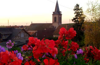 Eglise pendant au soleil couchant avec des fleurs rouges en premier plan