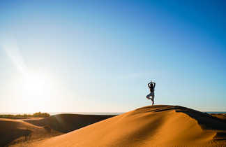 Femme faisant du yoga sur une dune de sable