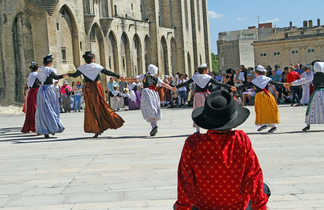 Foule joyeuse en train de danser une farandole typique provençale devant le chateau d'Avignon