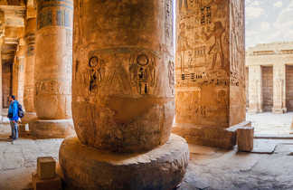 Voyageur devant les hiéroglyphes sur les murs du temple de Medinet Habu à Louxor