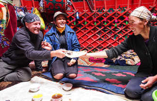 Partage du repas entre les voyageurs et les habitants dans une yourte en Kirghisie