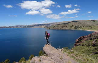 Randonneuse sur une pierre qui surplombe le lac Titicaca