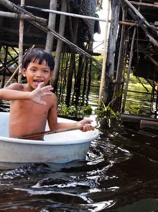 Enfant Cambodgien se baignant dans un lac proche d'un village sur pilotis