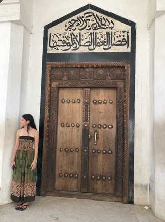 Jeune fille devant une porte stylisée à Zanzibar