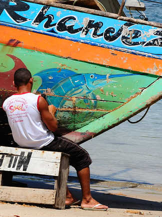 Pêcheurs en train de réparer son bateau sur une plage au Brésil