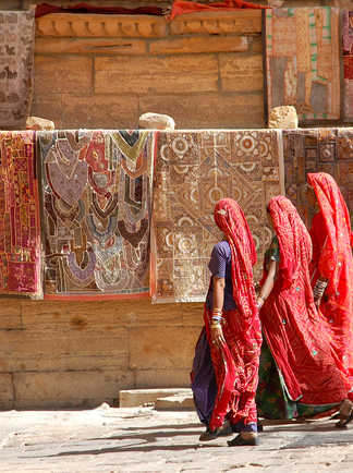 Trois indiennes en sari marchants devant un mur coloré, Rajasthan