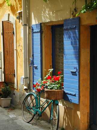 Vélo fleuri devant une jolie maison provençales aux volets bleus