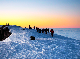 Groupe de randonneurs durant l'ascension finale du Kilimandjaro au lever de soleil en Tanzanie