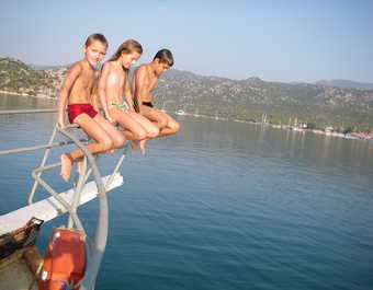 Enfants assis sur le pont avant d'un bateau au milieu de la mer