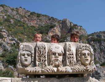 Enfants se cachant derrière un morceau de pierre sculptée