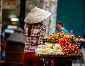 Femme vietnamienne au marché et son vélo rempli de fruits