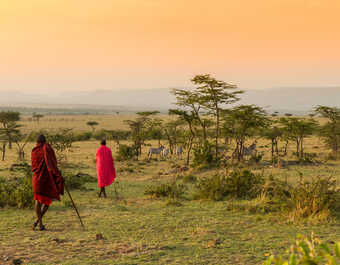 Masai marchant dans la brousse au coucher de soleil au Kenya