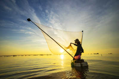 Pêcheur indonésien  jetant son filet au coucher du soleil