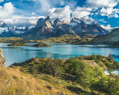 Lac bleu sur fond de montagnes enneigées et ciel nuageux Torres del paine