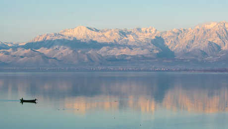 lac Shkodra, reflet des montagnes et un petit bateau de pêche au Monténégro