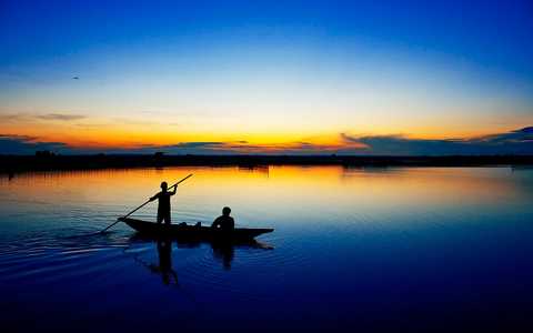Bateau sur la lagune de Tam Giang au coucher de soleil au Vietnam