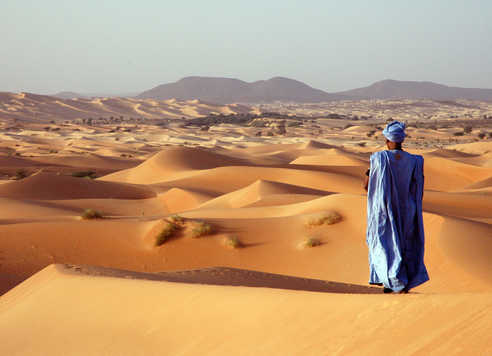 Touareg observant le coucher de soleil sur les dunes en Mauritanie