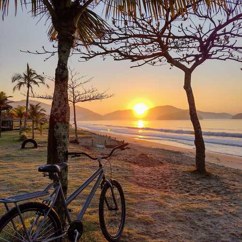En premier plan, un vélo sur une plage au coucher de soleil à Praia