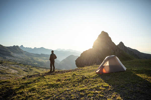 Homme se tenant debout regardant les montagnes avec une tente
