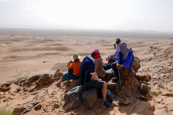 Groupe de randonneurs en pause sur une dune de sable dans le désert au Maroc
