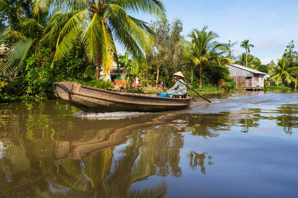 Habitant local au Vietnam sur une barque traditionnelle dans le delta du Mekong