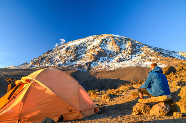 Randonneur regardant le Kilimandjaro devant son campement en Tanzanie