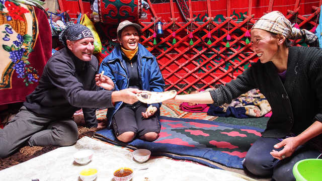 Partage du repas entre les voyageurs et les habitants dans une yourte en Kirghisie