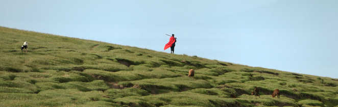 Homme masai avec sa tenue traditionnelle  flottant avec le vent dans les terres du rift en Tanzanie