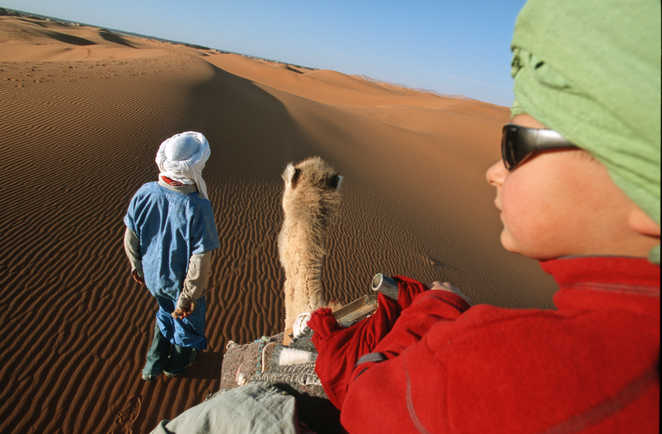 Enfant sur son chameau, face au désert, Maroc