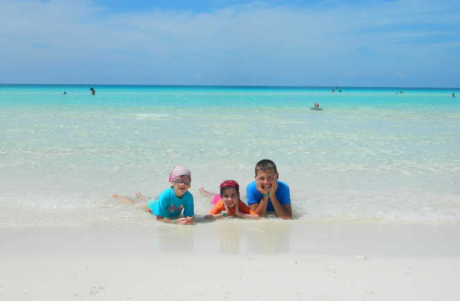 Enfants en bord de plage, allongés dans l'eau à Cayo Santa Maria à Cuba