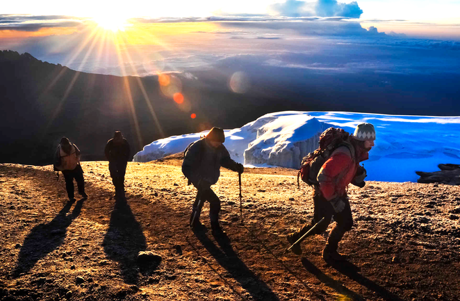 Groupe de randonneurs durant l'ascension finale du Kilimandjaro au lever de soleil en Tanzanie