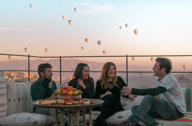 Quatre amis prenant leur déjeuner en plein air avec une belle vue sur les ballons en Cappadoce